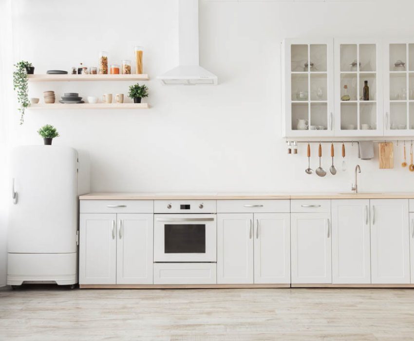 Minimal light scandinavian kitchen interior. White furniture with utensils, shelves with crockery and plants in pots, small refrigerator near window, panorama, empty space